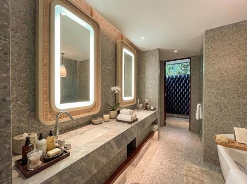 a bathroom with a tub and a large mirror at Riahi Villas by Swiss-Belhotel, Nirup Island in Belakangpandang