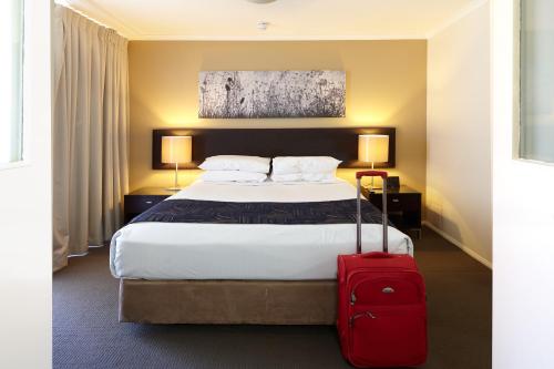 a hotel room with a bed with a red suitcase at West End Central Apartments in Brisbane