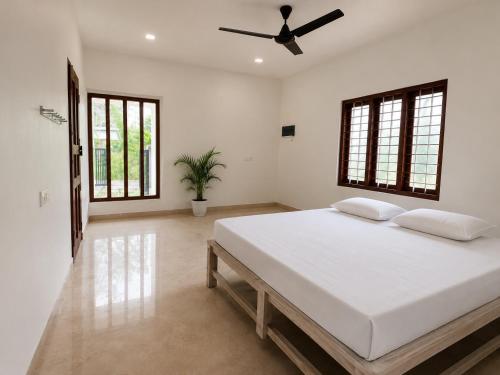 a bedroom with a large bed with a ceiling fan at Vedic villa Cherai beach in Cochin