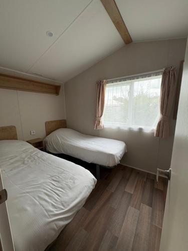 two beds in a small room with a window at Distel&Meer in Kropswolde