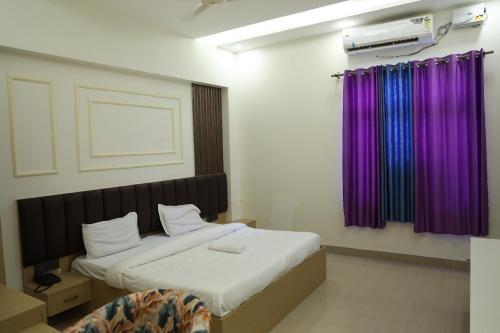 a bedroom with a large bed with purple curtains at Shree Krishna Hotel & Restraunt in Pātolī