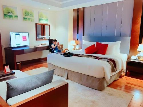 a woman sitting on a large bed in a hotel room at Summer Hotel in Dong Quan