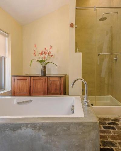a bathroom with a white tub and a vase of flowers at udesh hotel in Minuwangoda