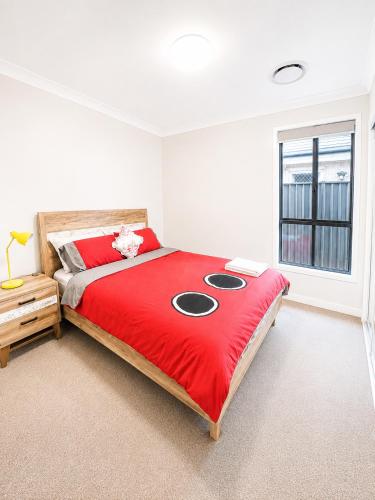 a bedroom with a large bed with a red blanket at 4 Bedrooms Home in Gledswood Hills
