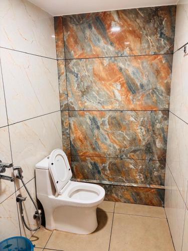 a bathroom with a toilet and a marble wall at Tvm stays in Trivandrum