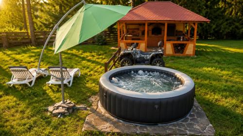 a hot tub with an umbrella next to a gazebo at Casa Dragomir in Plaiu Şarului