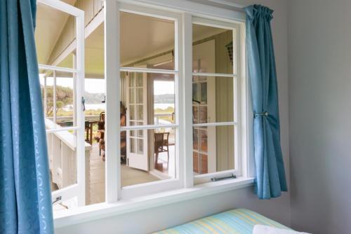 a room with a window with blue curtains at Russell-Orongo Bay Holiday Park in Russell
