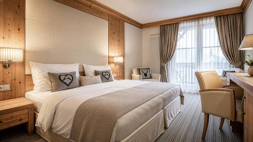 a hotel room with a large bed and a desk at Taubers Unterwirt Aktiv & Vitalhotel in Feldthurns