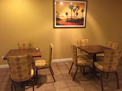 a dining room with two tables and chairs and a painting at Chula Vista Inn in Chula Vista
