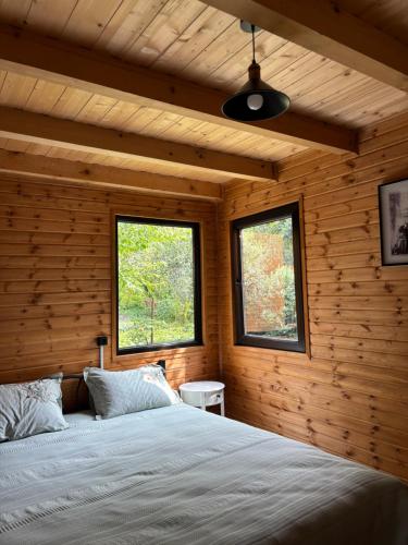 a bedroom with wooden walls and a bed with two windows at Babitouli-3 in Niabauri
