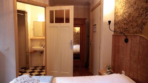 a bedroom with a bed and a bathroom with a sink at Uylenburg- Du Midi in Delft