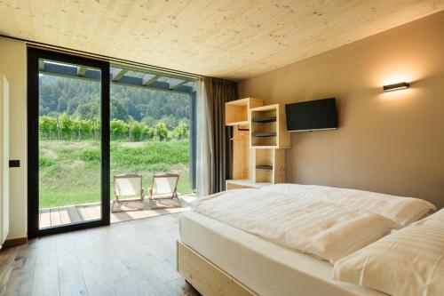 a bedroom with a large bed and a large window at Agriturismo Maso Loera in Pelugo