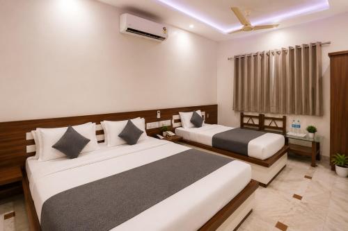 a bedroom with two beds and a window at Hotel Bhakti Rajkot I Hotel in Rajkot I Best Hotel in Rajkot in Rajkot