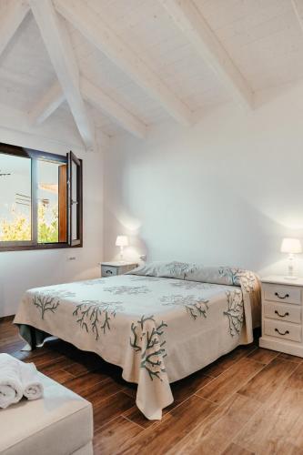 a white bedroom with a bed and a window at VILLA INDIPENDENTE AL MARE BUDONI in Tanaunella