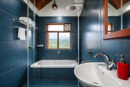 a blue bathroom with a tub and a sink at Hill Crest Resort - Coorg in Madikeri