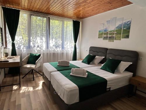 a bedroom with two beds and a desk and window at Къща Петя село Орешак in Troyan