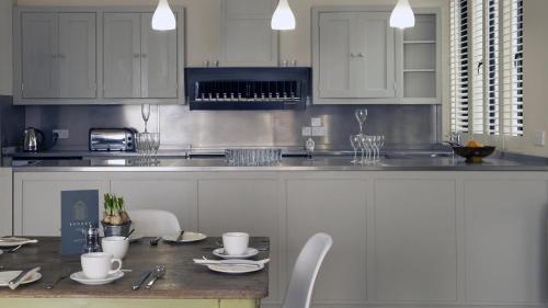 a kitchen with white cabinets and a table and chairs at Brooks Guesthouse Bristol in Bristol