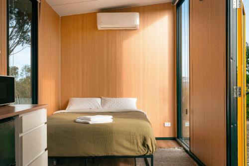 a small bedroom with a bed and a window at Raya and Aiden Farm House by Tiny Away in Cooma
