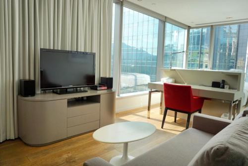 a living room with a flat screen tv and a piano at Twenty One Whitfield in Hong Kong
