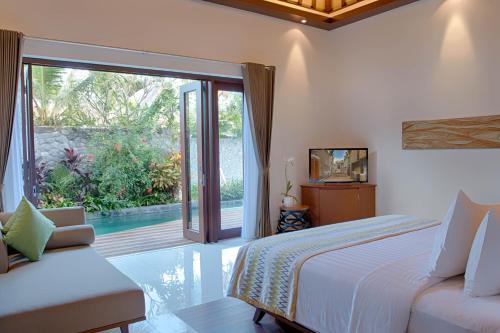 a bedroom with a bed and a sliding glass door at MERUSAKA Nusa Dua in Nusa Dua