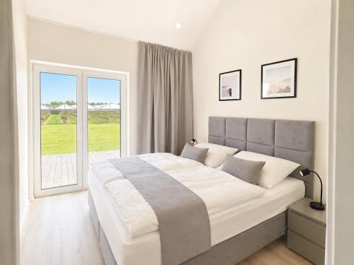 a white bedroom with a large bed and a window at Ferienhaus Elbdeichblick 1 in Haselau