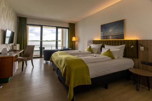 a hotel room with a bed and a desk and a window at Seehotel Berlin-Rangsdorf in Rangsdorf