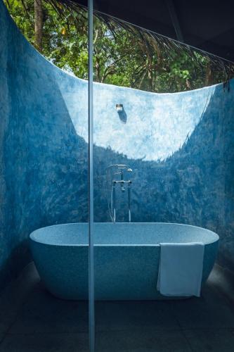a blue bathroom with a tub with a window at SAMA The Silver Creek in Bogmalo