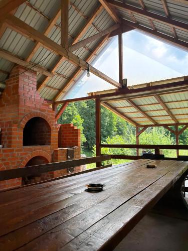 a wooden table in a pavilion with a brick oven at Colț de Vâlsan in Brăduleţ