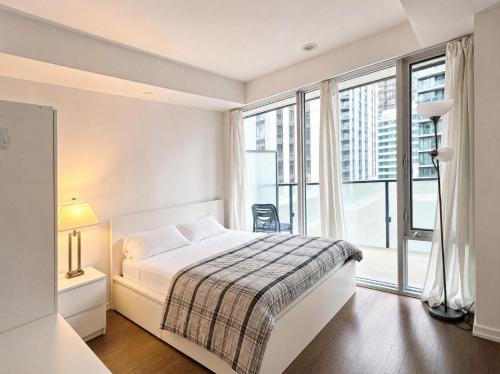 a white bedroom with a bed and a large window at Toronto Skyline Center Hotel in Toronto