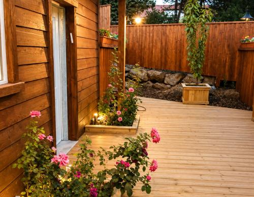 a wooden porch with flowers on the side of a house at BeLev Odem in Odem