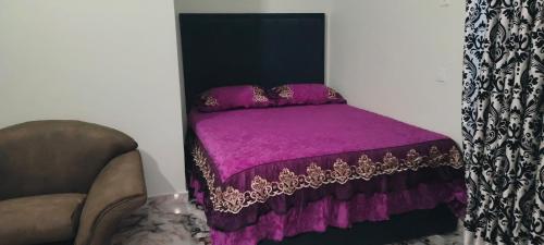a small bedroom with a purple bed with a chair at Optizee Hotel and Suites in Agege