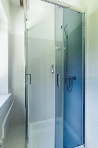a shower with a glass door in a bathroom at Parkova - pokoje hotelowe in Gołdap