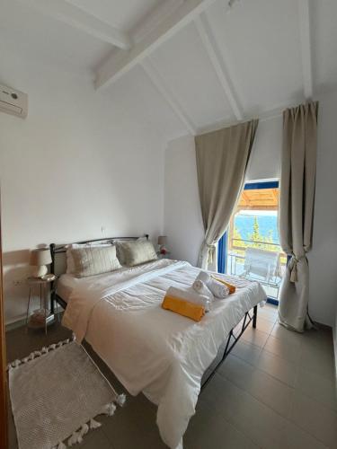 a white bedroom with a large bed and a window at Calmora by the Sea in Ancient Epidauros