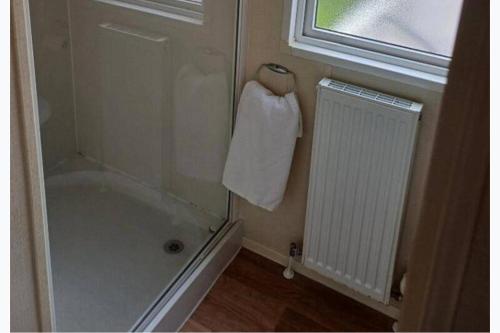 a bathroom with a shower and a towel on a window at 3-Bed Caravan Sleeps 7 with Indoor Pool in Wigton