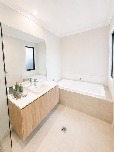 a white bathroom with a tub and a sink at 4 Bedrooms Home in Gledswood Hills