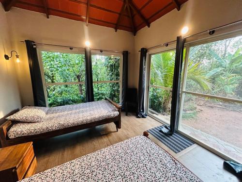 a room with two beds and large windows at Janapriya Villa 2 in Mudigere