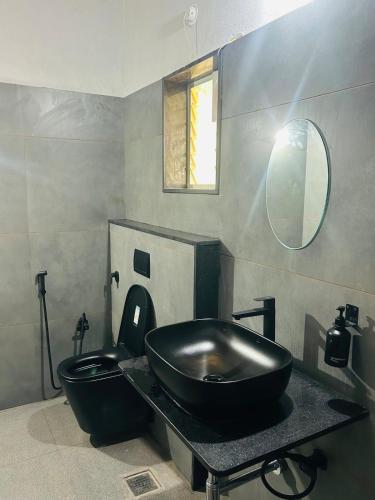 a bathroom with a black sink and a toilet at Janapriya Villa 2 in Mudigere
