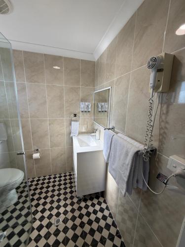 a bathroom with a toilet and a sink and a shower at Coffs Shearwater Motel in Coffs Harbour