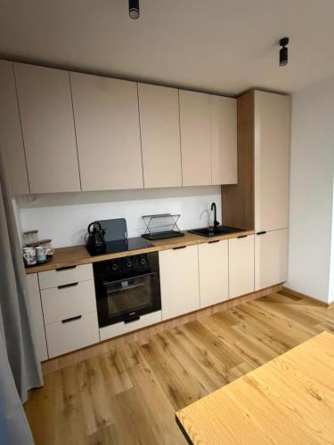 a kitchen with white cabinets and a wooden floor at Apartament Venis ul Jodłowa in Opole