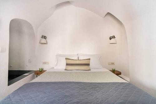 a white bedroom with a large bed with two lights at Villa LuxL in Fira