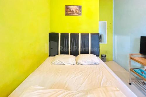 a bed in a room with a yellow wall at Penginapan Gindo Sidebuk Debuk Berastagi RedPartner in Berastagi
