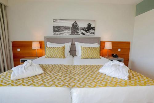 a bedroom with a bed with two white towels on it at Luna Arcos Hotel Nature & Wellness in Arcos de Valdevez