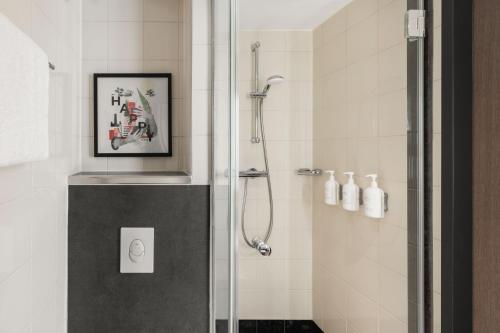 a bathroom with a shower with a picture on the wall at Spark by Hilton Essen City Centre in Essen