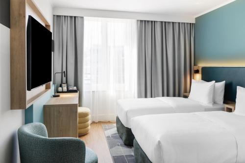 a hotel room with two beds and a television at Spark by Hilton Essen City Centre in Essen