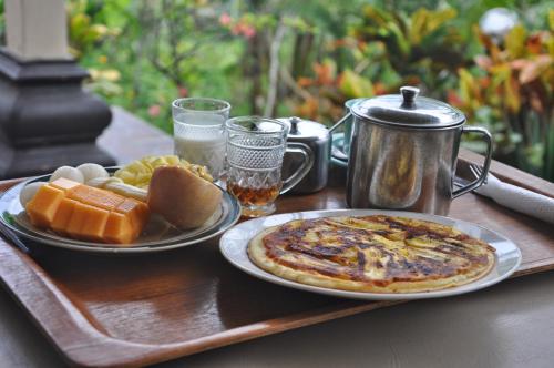 a table with a tray with a pizza and some fruit at Surya Homestay in Selemadeg