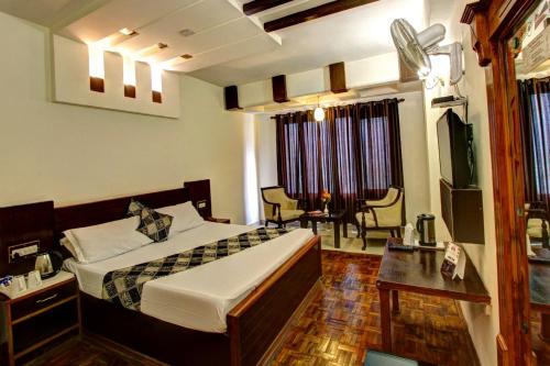 a bedroom with a bed and a desk and a tv at New Daffodil Classic Manali in Manāli
