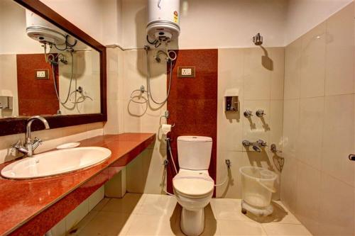 a bathroom with a sink and a toilet and a mirror at New Daffodil Classic Manali in Manāli