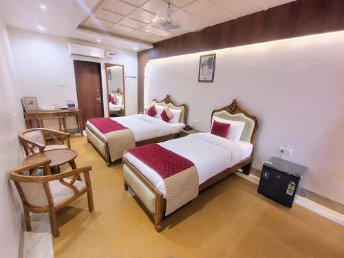 a hotel room with two beds and a chair at MVT Guesthouse & Restaurant in Vrindāvan