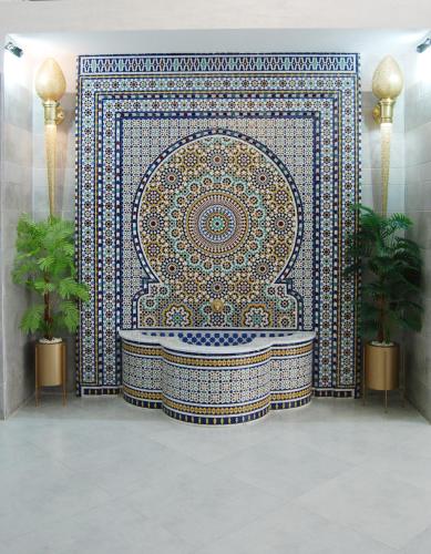 a bathroom with a large mosaic tile wall with a tub at Hôtel Asswar Al Madina in Fez