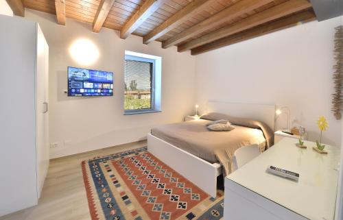 a bedroom with a bed and a desk and a window at Alla Corte del Gallo in Tricesimo